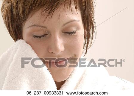 Stock Image - Head and shoulders front view young woman with short hair in a dressing gown holding the sleeve to her face eyes closed. Fotosearch