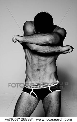Picture - Male wearing black underpants and standing with head in arms. Fotosearch
