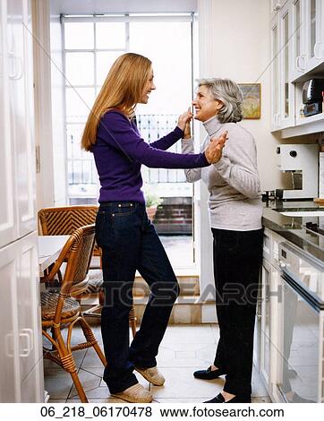 mother grandmother granny inside kitchen talking happy smiling affectionate trousers black purple grey long blonde hair woman portrait winter family friends View Large Photo Image Stock Photo - mother grandmother granny inside kitchen talking happy smiling affectionate trousers black purple grey long blonde hair woman portrait winter family friends. Fotosearch