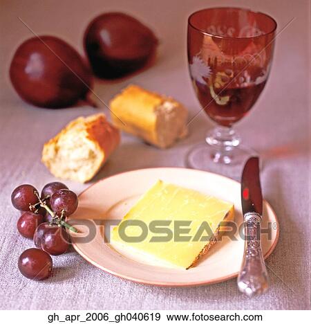 Slice of cheese on plate with grapes to the side and baguette in the background View Large Photo Image Stock Photo - Slice of cheese on plate with grapes to the side and baguette in the background. Fotosearch