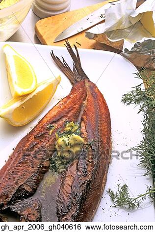 Stock Photograph - Smoked kippers with lemon and dil butter with two segments of lemon to the side.. Fotosearch