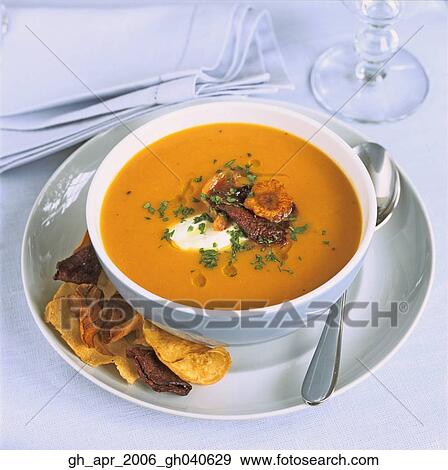 Stock Photo - Sweet potatoe and leek soup with crisps on the side and a spoon.. Fotosearch