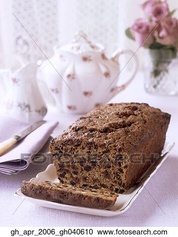 Stock Image - Tea brack loaf cake with sultana's with china tea pot and jug in the background.. Fotosearch