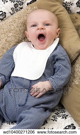 View from above of a baby wearing a blue and white striped jumper with white bib lying on a pillow and yawning. View Large Photo Image Stock Photograph - View from above of a baby wearing a blue and white striped jumper with white bib lying on a pillow and yawning.. Fotosearch