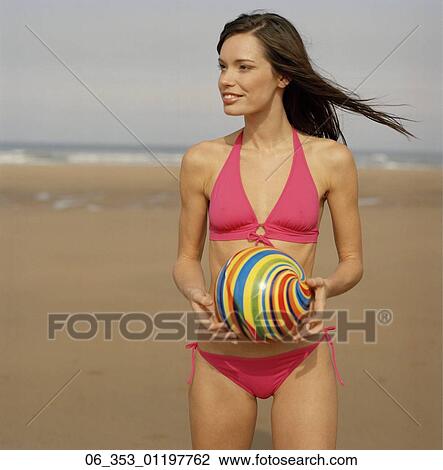 été Beauté Position Femme Sur A Plage Porter A Rose Halterneck Bikini Tenue A Spirale Coloré Balle Cheveux Souffler Dans Vent Banque