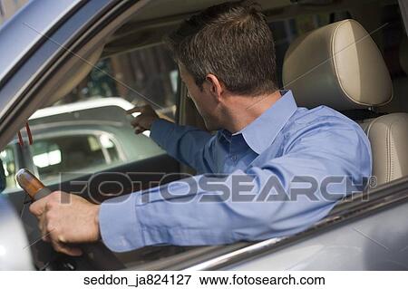 A man wearing a blue button-down shirt sitting in a car experiencing road rage. View Large Photo Image Stock Photo - A man wearing a blue button-down shirt sitting in a car experiencing road rage.. Fotosearch
