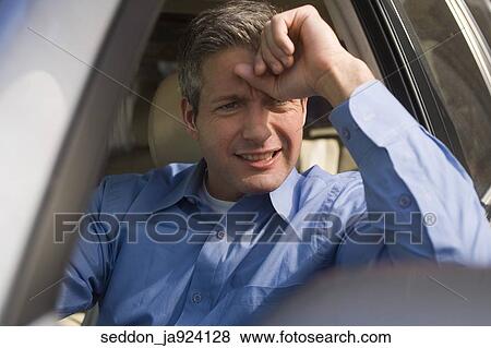 A man wearing a blue button-down shirt sitting in a car experiencing road rage. View Large Photo Image Stock Photo - A man wearing a blue button-down shirt sitting in a car experiencing road rage.. Fotosearch