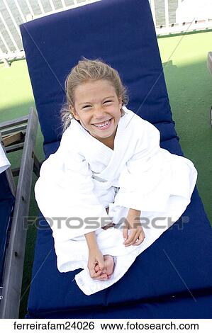 A young girl smiling wearing a white robe sitting on a lounge chair on the roof. View Large Photo Image Stock Photograph - A young girl smiling wearing a white robe sitting on a lounge chair on the roof.. Fotosearch