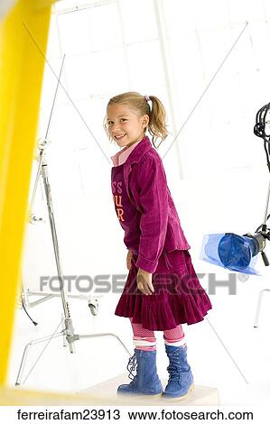 A young girl wearing a burgundy skirt outfit and blue boots in front of a white back drop. View Large Photo Image Stock Image - A young girl wearing a burgundy skirt outfit and blue boots in front of a white back drop. . Fotosearch