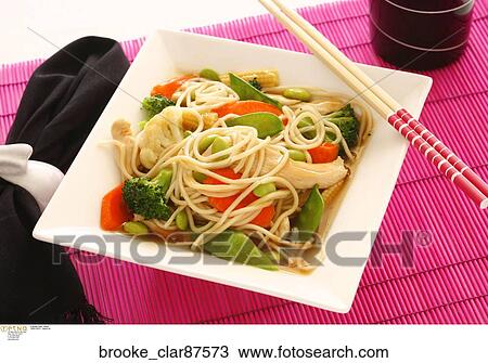 Stock Image - Asian Dish with noodles, broccoli, pea pods, cauliflower and tomatoes. Fotosearch