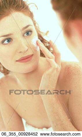 BeautyCropped image of woman looking at her reflection in the mirror whilst rubbing moisturiser into her cheeks View Large Photo Image Stock Image - BeautyCropped image of woman looking at her reflection in the mirror whilst rubbing moisturiser into her cheeks . Fotosearch