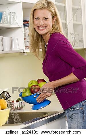 Blonde female in her 30's holding a bowl of apples in a kitchen. View Large Photo Image Stock Photography - Blonde female in her 30's holding a bowl of apples in a kitchen.. Fotosearch
