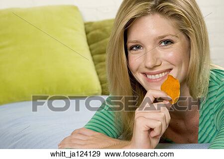 Stock Photo -  Blonde woman in her 20's eats potato chips. Fotosearch
