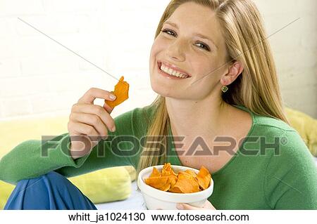 Blonde woman in her 20's holding a bowl eating potato chips View Large Photo Image Stock Image - Blonde woman in her 20's holding a bowl eating potato chips. Fotosearch