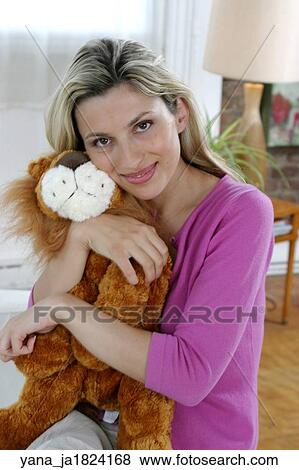 Stock Photo -  Blonde woman in her 20's holding a stuffed lion. . Fotosearch