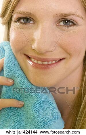 Blonde woman in her 20's holds a blue towel to her face. View Large Photo Image Picture - Blonde woman in her 20's holds a blue towel to her face.. Fotosearch