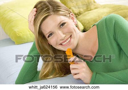Blonde woman in her 20's lying on a bed eats potato chips. View Large Photo Image Stock Photograph - Blonde woman in her 20's lying on a bed eats potato chips.. Fotosearch