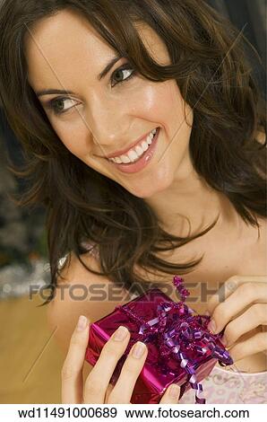 Brunette female with shoulder length hair holding a wrapped gift and smiling View Large Photo Image Stock Photo - Brunette female with shoulder length hair holding a wrapped gift and smiling. Fotosearch