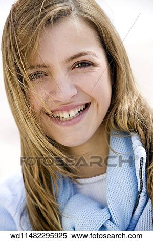 Stock Photography - Close up of female with long blonde hair wearing pale blue jumper looking to camera smiling showing teeth. . Fotosearch