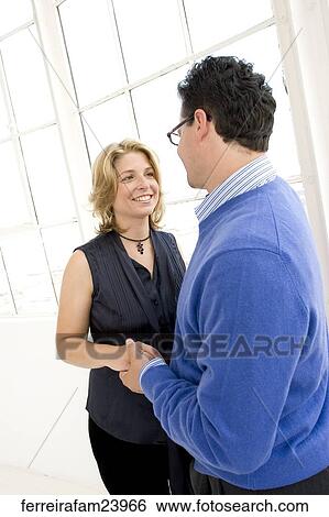 Stock Photograph -  Couple in their 30's being affectionate facing each other holding hands posing in a studio. Fotosearch