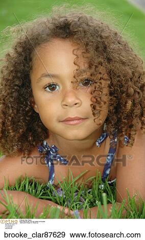 Ethnic Little Girl With Curly Hair Outside On The Grass Stock