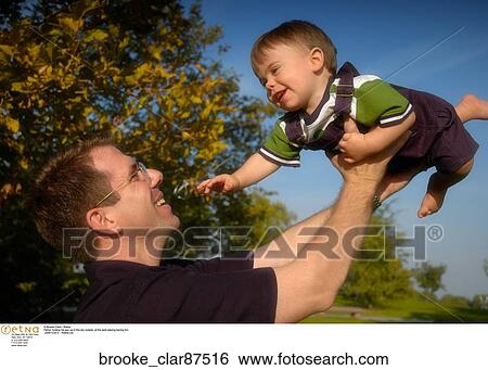 Father holding his son up in the sky outside at the park playing having fun. View Large Photo Image Stock Photograph - Father holding his son up in the sky outside at the park playing having fun.. Fotosearch