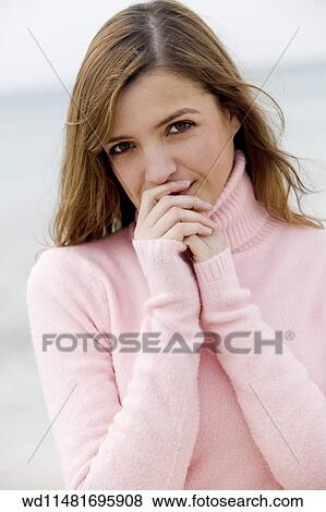 Female with long blonde hair wearing pink poloneck jumper hands to mouth looking to camera head tilted. View Large Photo Image Stock Photo - Female with long blonde hair wearing pink poloneck jumper hands to mouth looking to camera head tilted. . Fotosearch