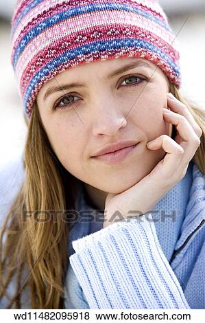 Female with long blonde hair wearing multicoloured knitted hat and pale blue jumper hand to chin finger tips on cheek looking to camera unsmiling. View Large Photo Image Stock Photo - Female with long blonde hair wearing multicoloured knitted hat and pale blue jumper hand to chin finger tips on cheek looking to camera unsmiling. . Fotosearch