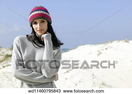 Stock Image - Female with long straight brunette hair wearing knitted hat. Fotosearch