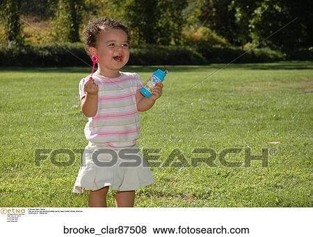 Little girl at the park blowing bubbles spring happy todderl african american View Large Photo Image Stock Photo - Little girl at the park blowing bubbles spring happy todderl african american. Fotosearch