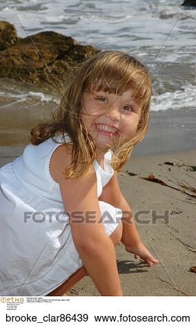 Little girl on the beach playing in the sand smiling" View Large Photo Image Stock Photo - Little girl on the beach playing in the sand smiling". Fotosearch