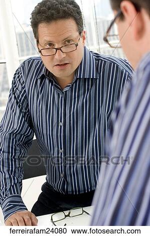 Man in his 30's wearing glasses wearing a striped button down shirt looking at his reflection in a mirror View Large Photo Image Stock Image - Man in his 30's wearing glasses wearing a striped button down shirt looking at his reflection in a mirror. Fotosearch