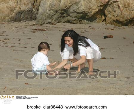 Mother playing with toddler on the beach in the sand View Large Photo Image Stock Photo - Mother playing with toddler on the beach in the sand. Fotosearch