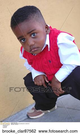 Portrait of a African American boy bending down in a sweater vest View Large Photo Image Stock Image - Portrait of a African American boy bending down in a sweater vest. Fotosearch