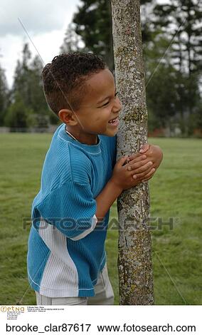 Portrait of a ethnic little boy playing outside by a tree View Large Photo Image Stock Photo - Portrait of a ethnic little boy playing outside by a tree. Fotosearch