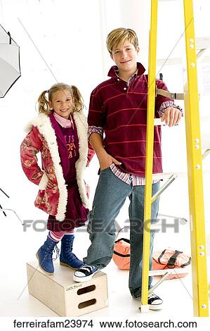 Portrait of a teenage boy and a young girl posing by a ladder the girl stands on a box. View Large Photo Image Picture - Portrait of a teenage boy and a young girl posing by a ladder the girl stands on a box.. Fotosearch