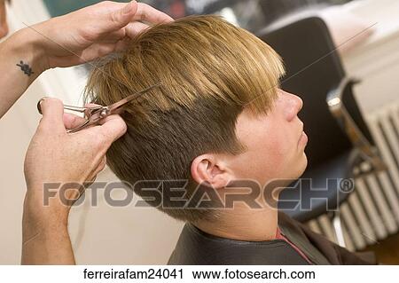 Stock Image -  Portrait of a teenage boy having a haircut in a salon. Fotosearch