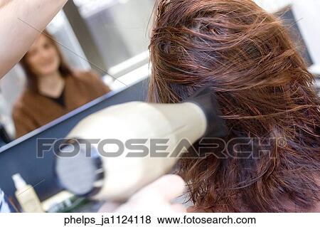 Portrait of a woman having her hair styled with a hair dryer. View Large Photo Image Stock Photo - Portrait of a woman having her hair styled with a hair dryer.. Fotosearch