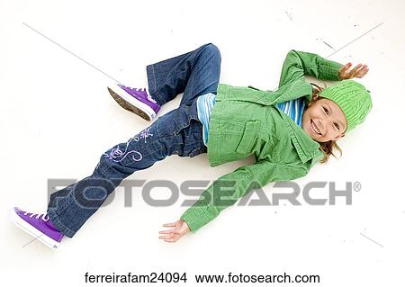 Portrait of a young girl lying on a white backdrop wearing a green coat and green hat and purple sneakers View Large Photo Image Picture - Portrait of a young girl lying on a white backdrop wearing a green coat and green hat and purple sneakers. Fotosearch