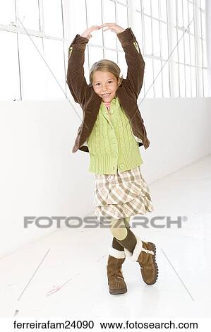 Stock Image -  Portrait of a young girl standing in front of a window wearing winter clothing. Fotosearch