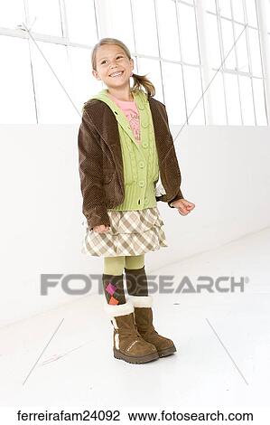 Portrait of a young girl standing in front of a window wearing winter clothing. View Large Photo Image Stock Image - Portrait of a young girl standing in front of a window wearing winter clothing.. Fotosearch