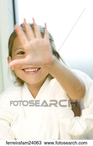 Stock Image -  Portrait of a young girl wearing a white robe getting a manicure in a salon.. Fotosearch