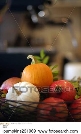 Stock Photo -  Still life image of a bowl of orange and white pumpkins with red pomegrantes. . Fotosearch