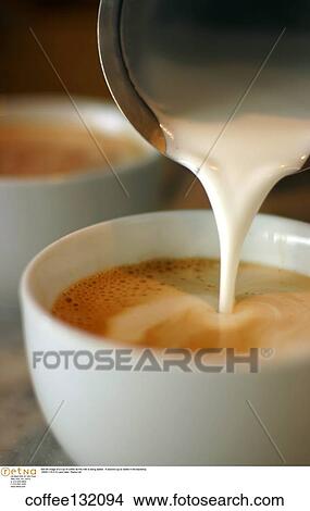 Still life image of a cup of coffee as the milk is being added. A second cup is visible in the backdrop. View Large Photo Image Picture - Still life image of a cup of coffee as the milk is being added. A second cup is visible in the backdrop.. Fotosearch