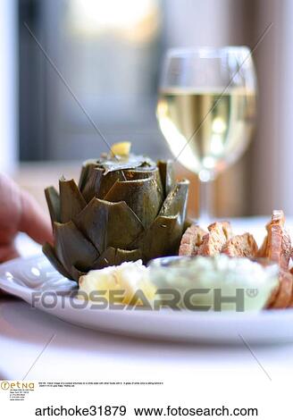 Still life indoor image of a cooked artichoke on a white plate with other foods with it. A glass of white wine is sitting behind it. View Large Photo Image Stock Photo - Still life indoor image of a cooked artichoke on a white plate with other foods with it. A glass of white wine is sitting behind it. . Fotosearch