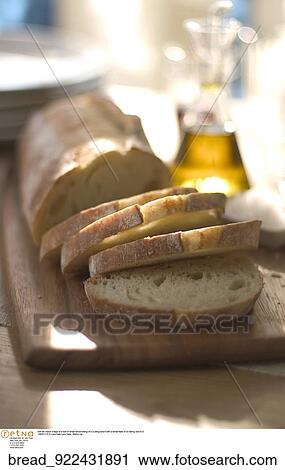 Still life indoor image of a loaf of bread sliced sitting on a cutting board with a small flask of oil sitting next to it. View Large Photo Image Stock Image - Still life indoor image of a loaf of bread sliced sitting on a cutting board with a small flask of oil sitting next to it.. Fotosearch