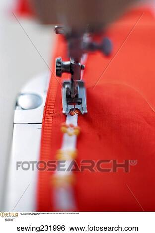 Stock Photograph -  Still life indoor image of a sewing machine attaching a white stripe. Fotosearch