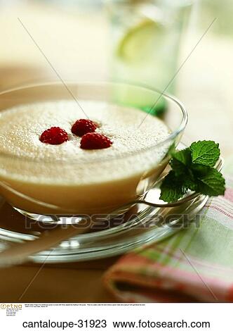Stock Image -  Still life indoor image of a cantaloupe puree in a bowl with three raspberries floating in the puree. There is a plate under the bowl where a spoon rests and a sprig of mint garnishes the bowl.. Fotosearch