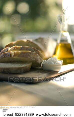 Still life indoor image of sliced bread sitting on a cutting board with a flask of oil sitting on the side. View Large Photo Image Stock Photo - Still life indoor image of sliced bread sitting on a cutting board with a flask of oil sitting on the side.. Fotosearch