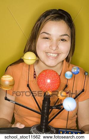 Stock Image -  Stock images of science related topics girl wearing an orange shirt showing off her solar system school project.. Fotosearch